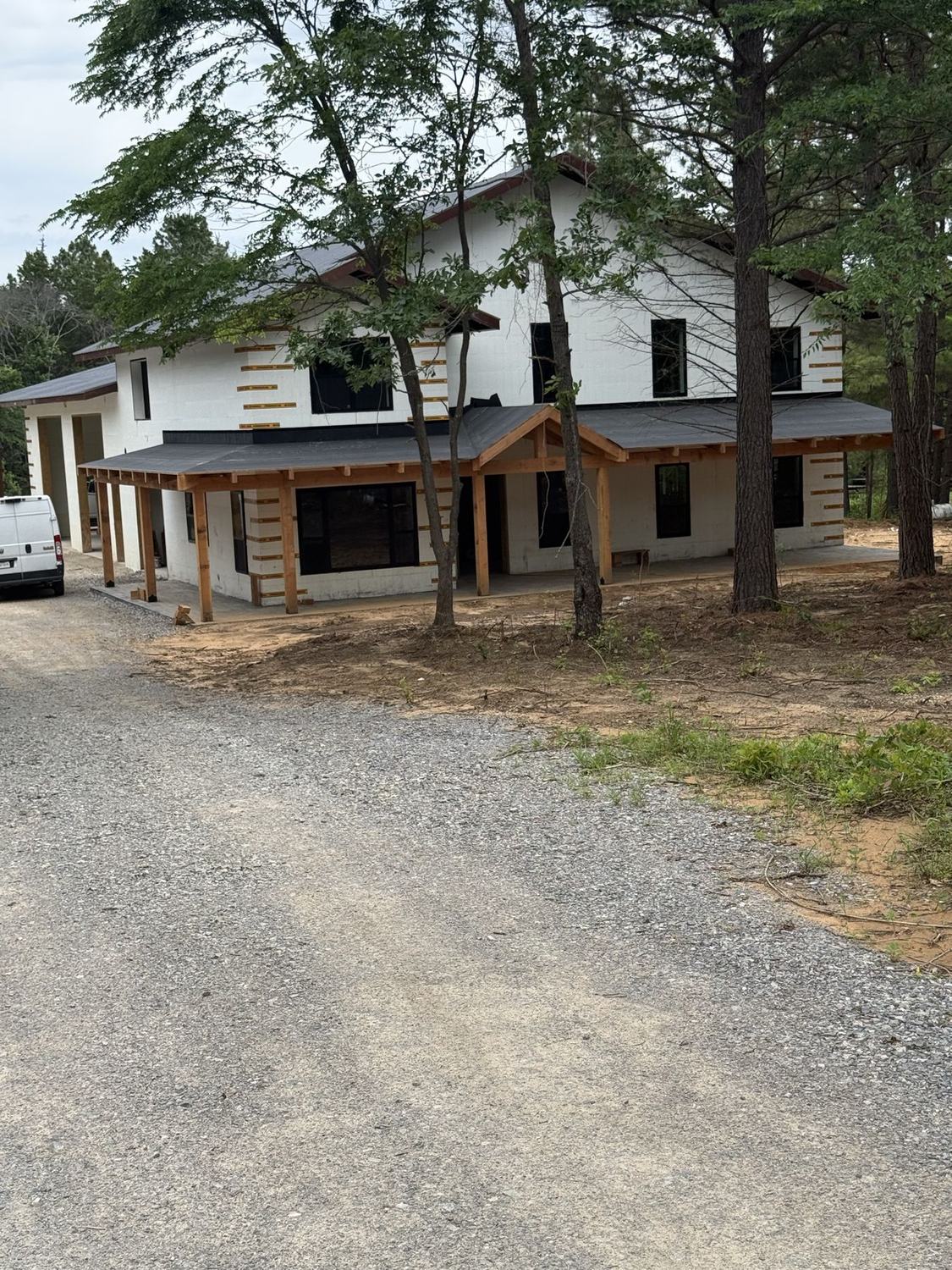 Two-story Visten ICF custom home with continuous foam envelope and covered porches, set among mature trees in North Texas