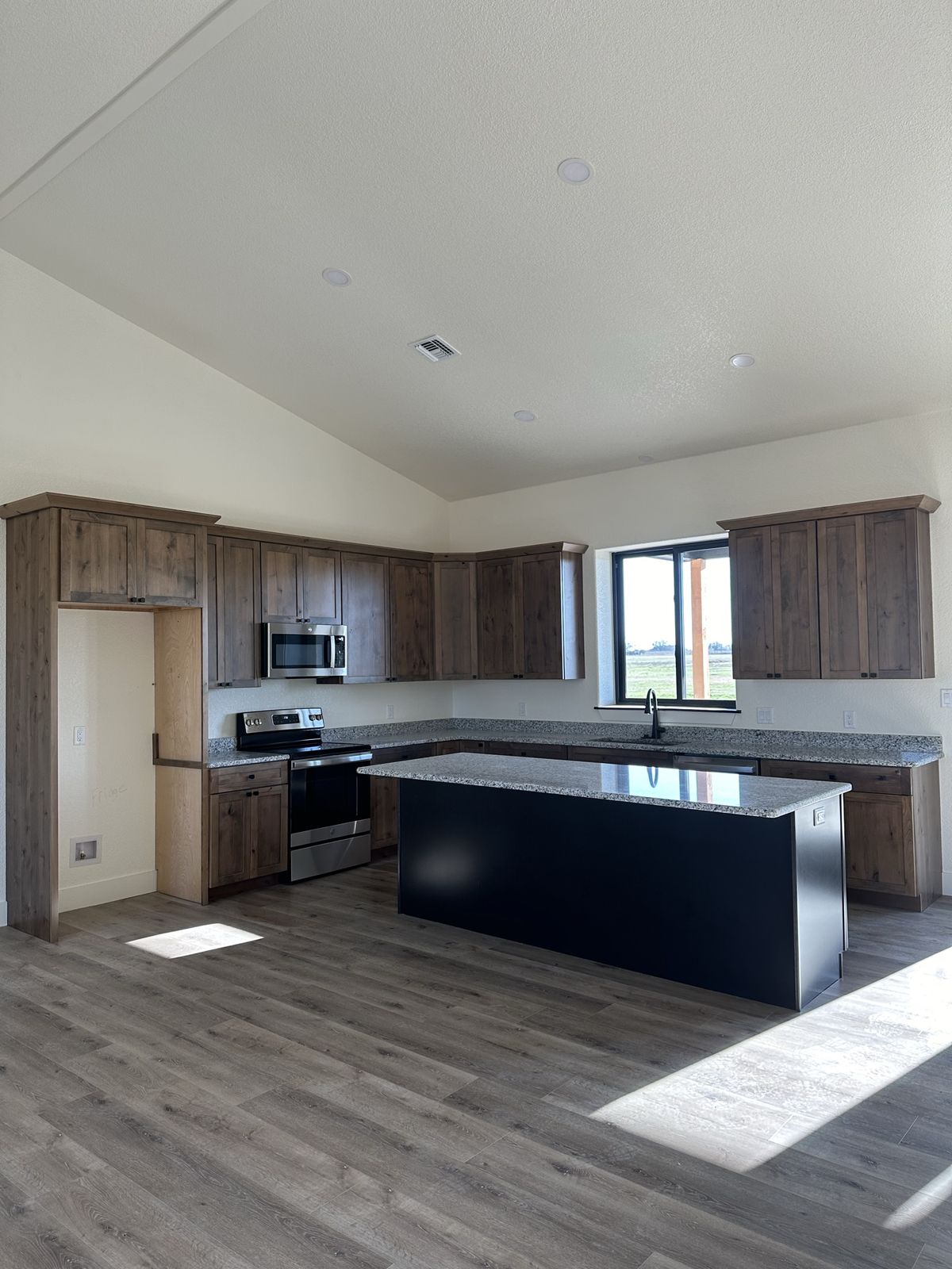 Custom ICF home kitchen with white shaker cabinetry, stone countertops, and wide-plank flooring in Burkburnett, Texas